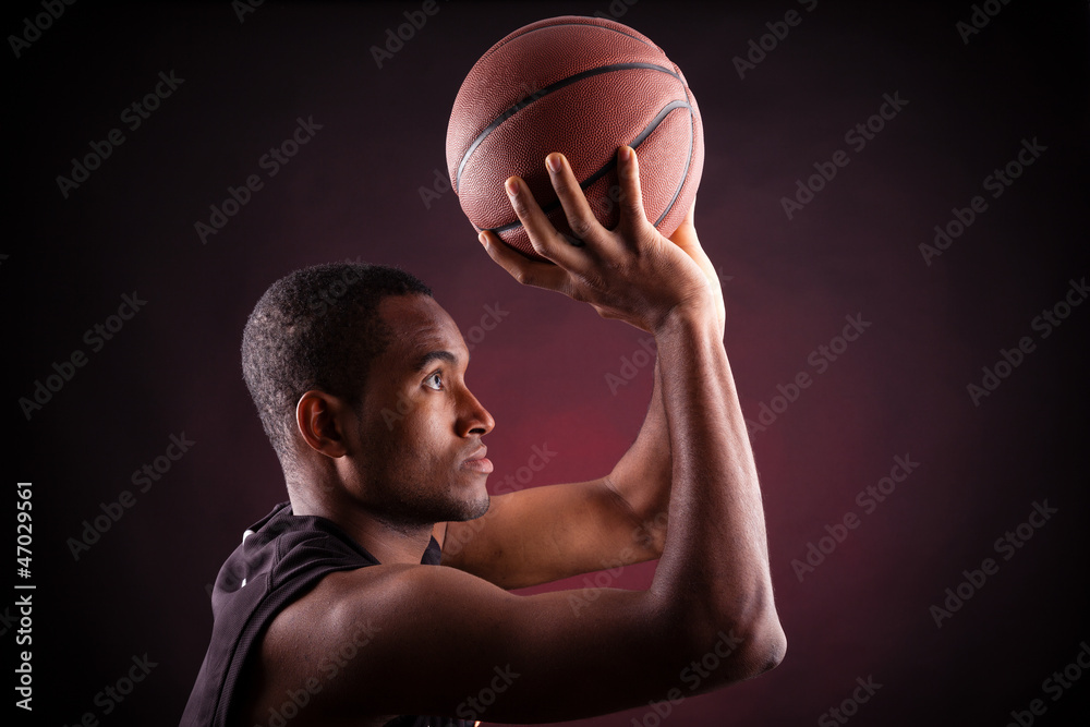 Portrait of a young male basketball player against black backgr Portrait of a young male basketball player against black backgr