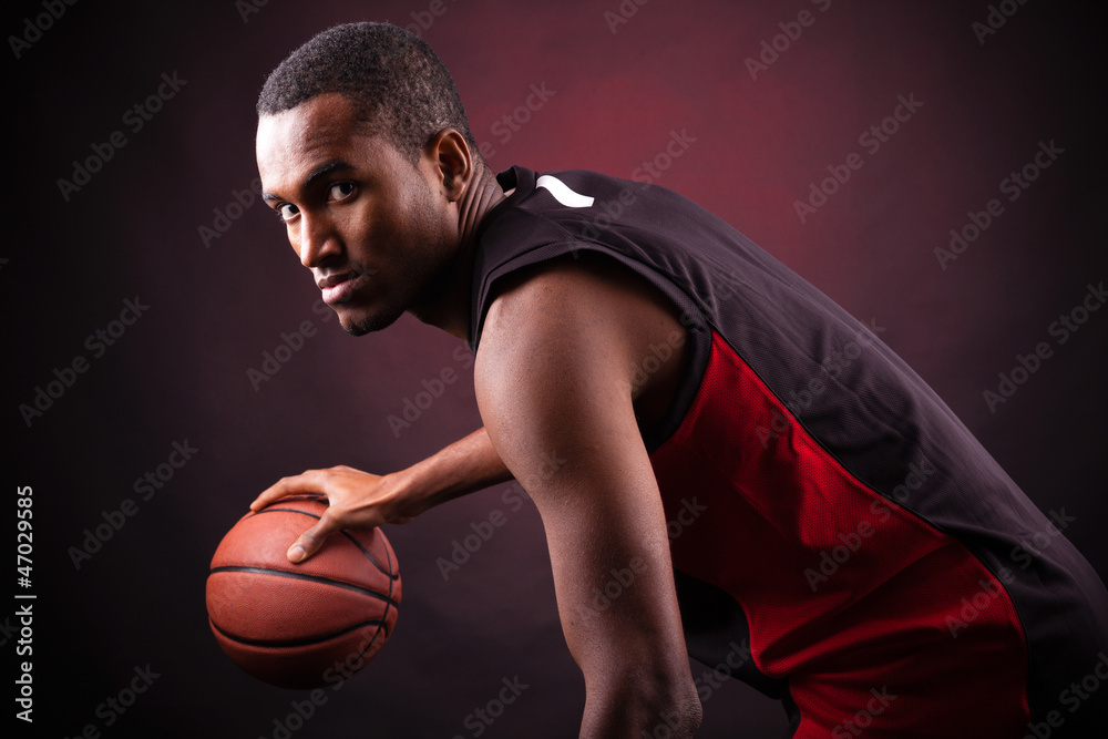 Portrait of a young male basketball player against black backgr Portrait of a young male basketball player against black backgr