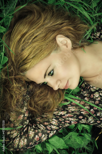 Close-up portrait of a young woman relaxing on grass