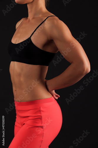 muscular female body against black background.