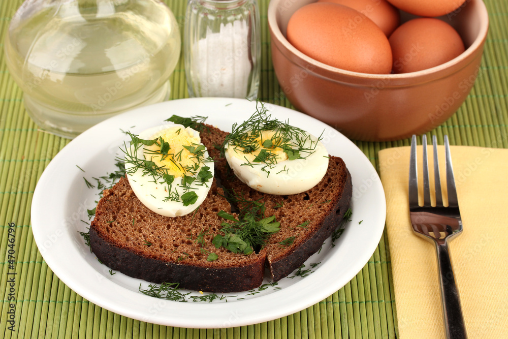Boiled eggs on dark bread on green background Boiled eggs on dark bread on green background