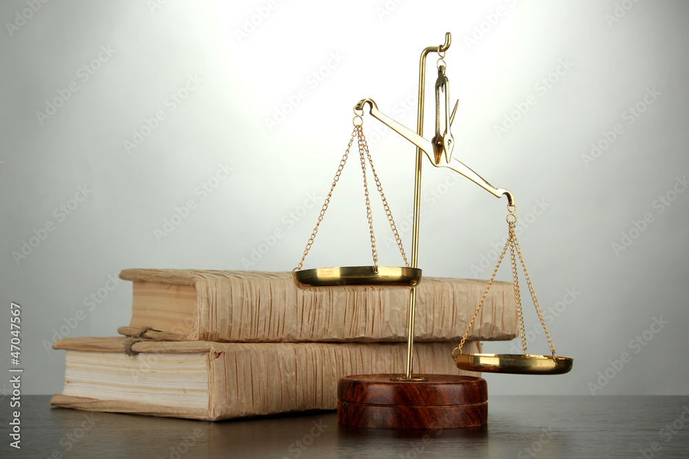 Gold scales of justice and books on grey background Gold scales of justice and books on grey background
