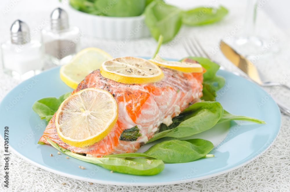 Baked salmon fillet with lemon and spinach on a plate Baked salmon fillet with lemon and spinach on a plate