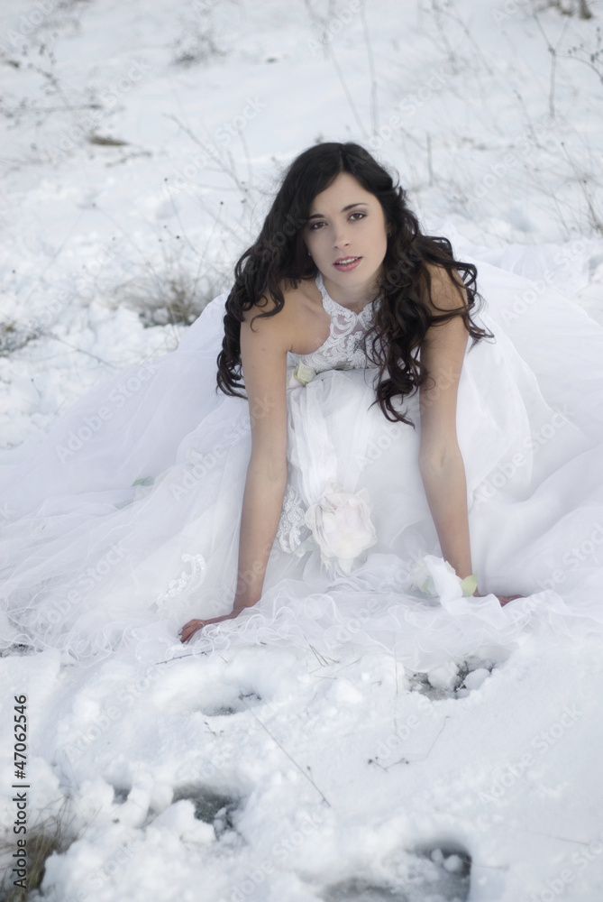 pretty young woman posing in wedding dress  on winter snow