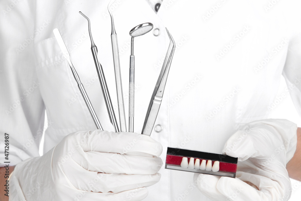 Fototapeta premium Set of dental tools and denture in dentists hands