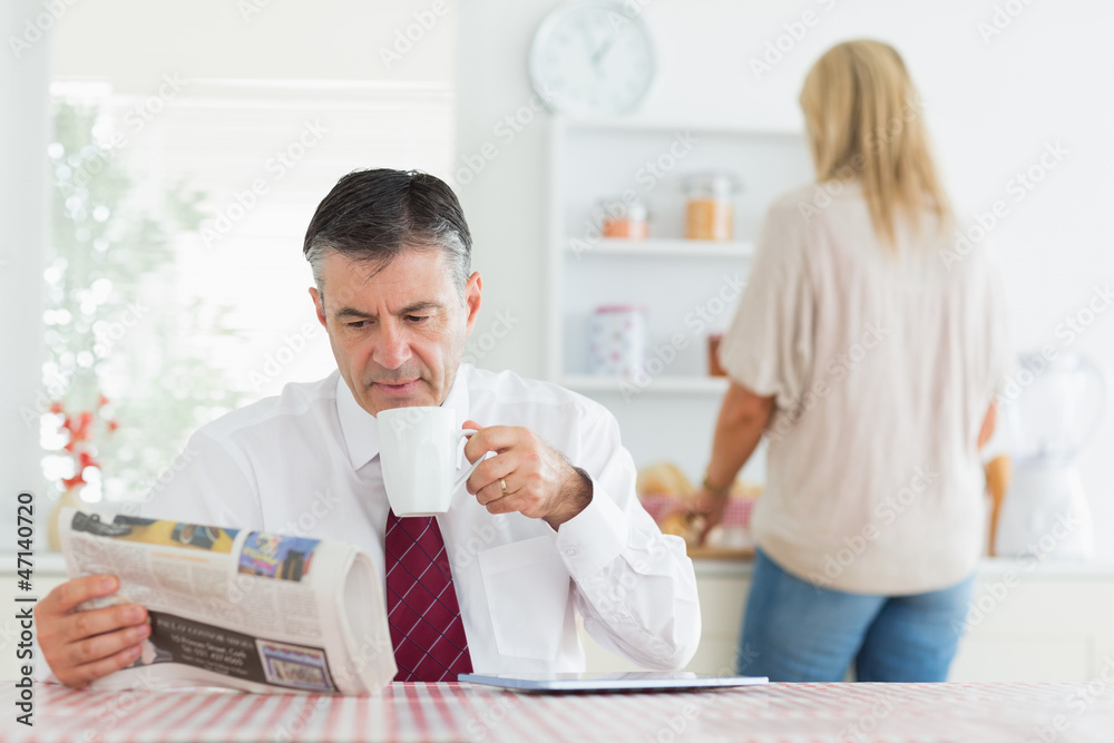 Man sitting at the kitchen table while reading a newspaper Man sitting at the kitchen table while reading a newspaper
