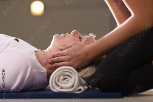 Foto Young therapist arranging crystals on female client for reiki th