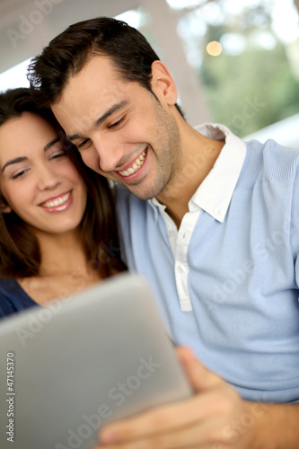 Smiling couple websurfing on internet with tablet