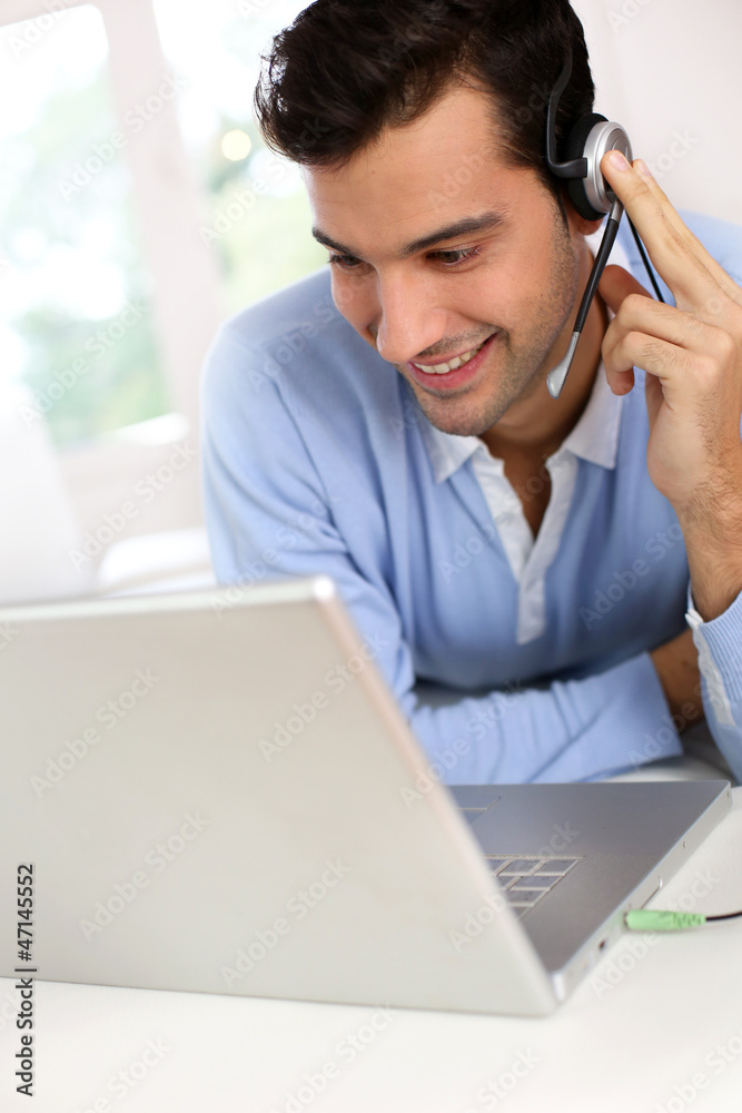 Young man with headset chating through webcamera Young man with headset chating through webcamera