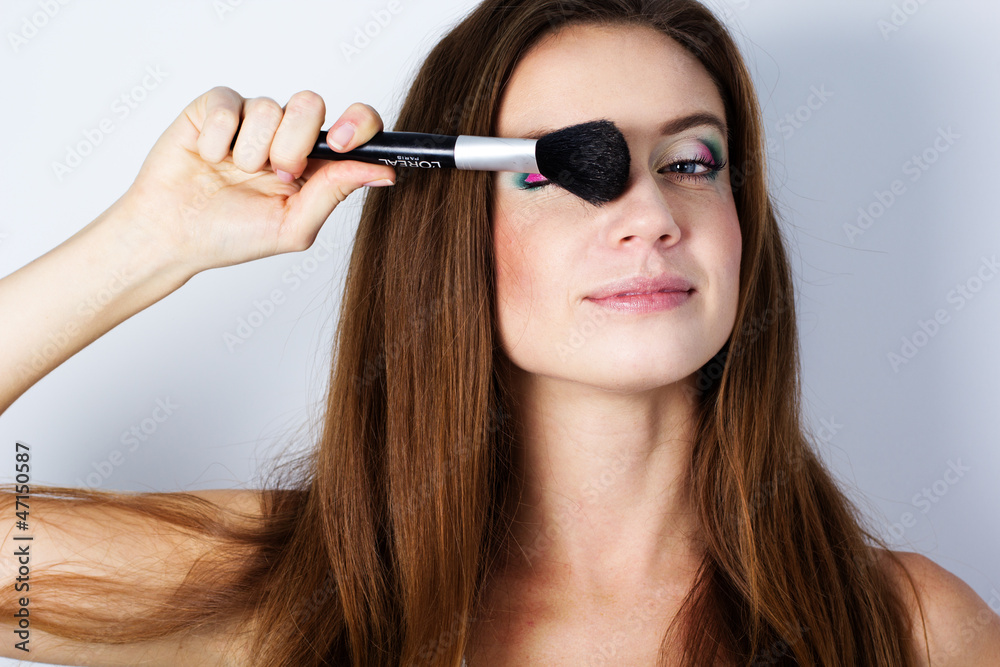 beautiful woman holding makeup brush over white beautiful woman holding makeup brush over white