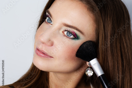 beautiful woman holding makeup brush over white