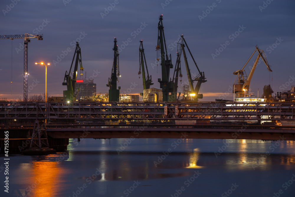 Big cranes and bridge at the shipyard at night.