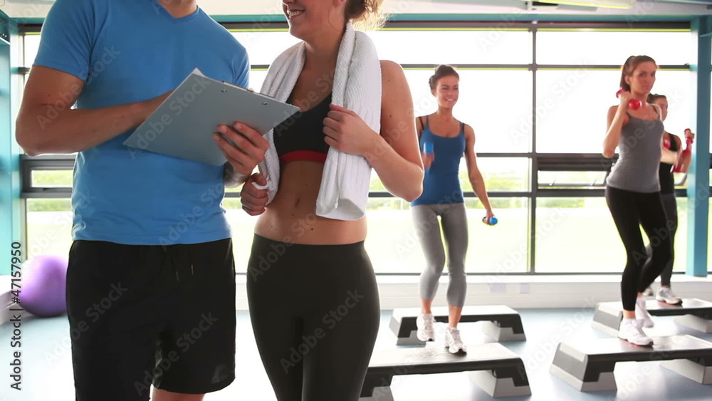 Women doing aerobics while trainer talking with woman Women doing aerobics while trainer talking with woman