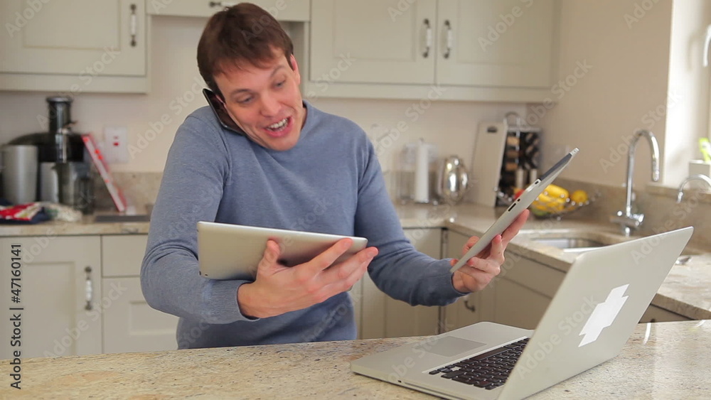 Man using laptop, mobile phone and two tablets busily Man using laptop, mobile phone and two tablets busily