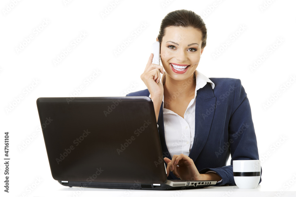 Business woman speaking on phone while using laptop Business woman speaking on phone while using laptop