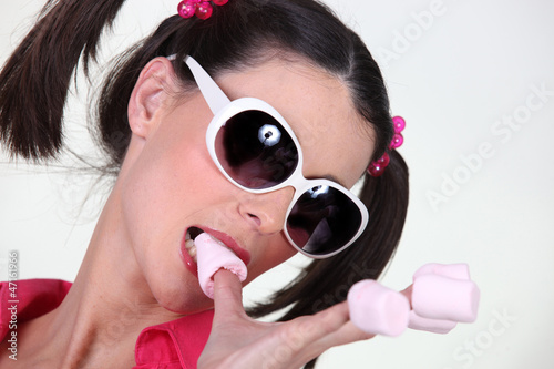 brunette with pigtails and sunglasses eating marshmallows photo