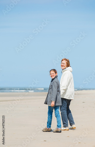 Girl and her grandmother walking on the beach