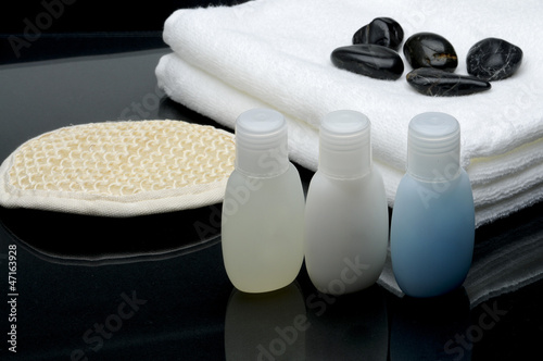 Spa setting, shampoo, towel, stones and bath glove