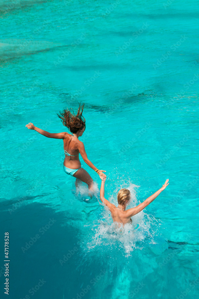 Two girls jumping in the sea