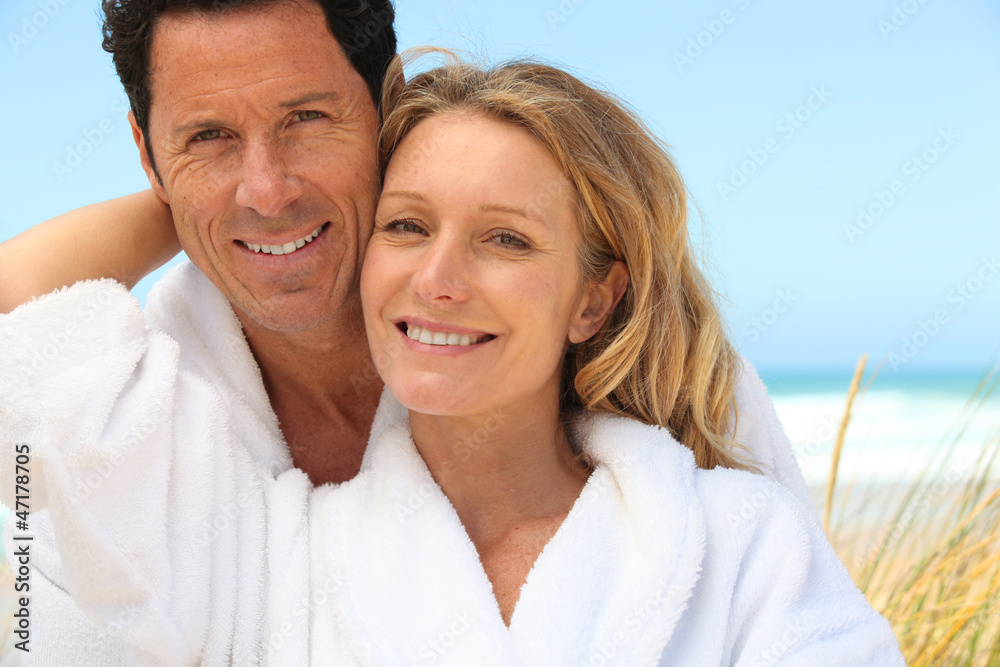 Happy couple wearing dressing gowns at the beach Happy couple wearing dressing gowns at the beach