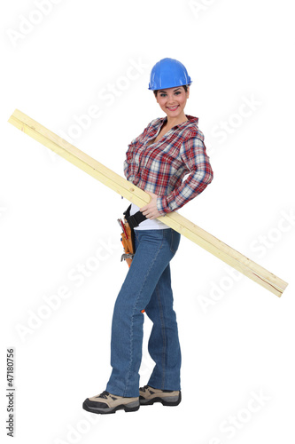 portrait of young female carpenter holding lumber