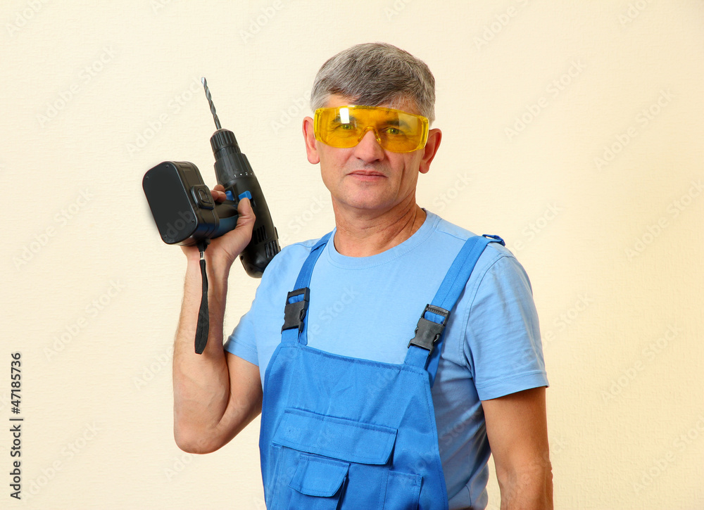 Builder with drill on wall background