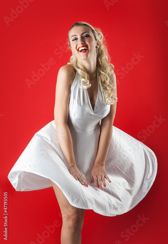 Blonde woman portrait with skirt flying on red background.