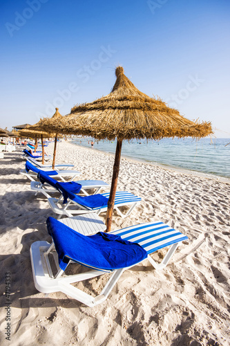 Nice beach with beach chairs and thatched umbrellas in Port El K