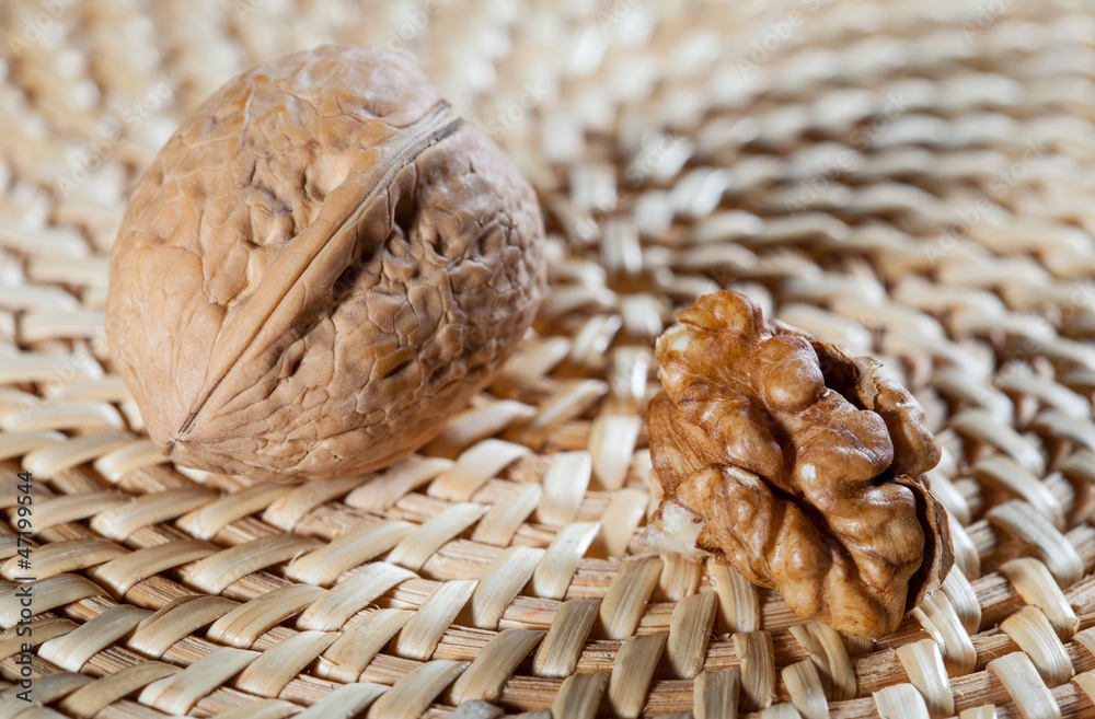 Whole walnut and walnut's kernel on straw background