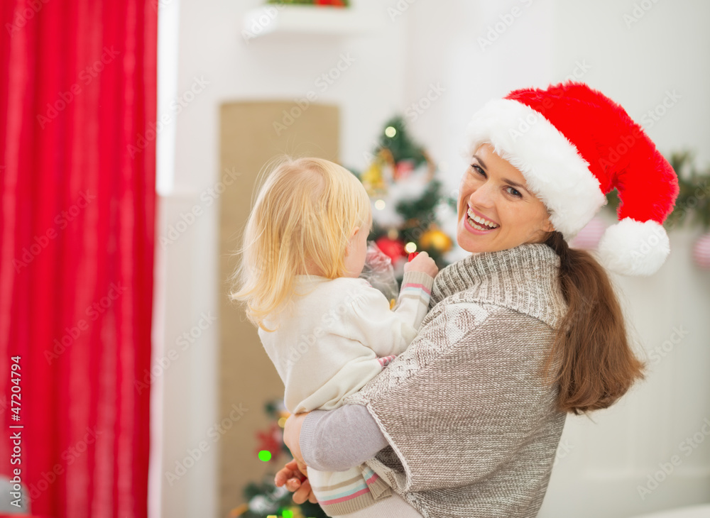 Mother holding baby in front of Christmas tree Mother holding baby in front of Christmas tree