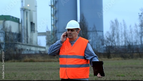 Foreman talking on the cell phone near the factory photo