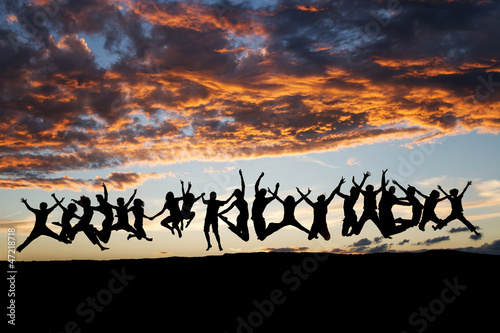 silhouetted large group of teens jumping after sunset