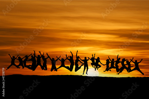 silhouetted large group of teens jumping in sunset