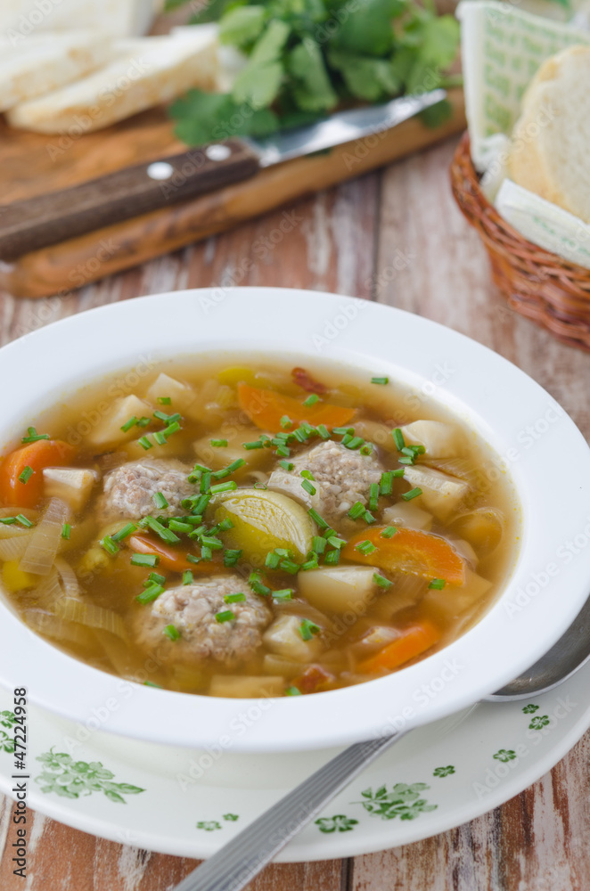 Plate of vegetable soup with meatballs on the wooden table