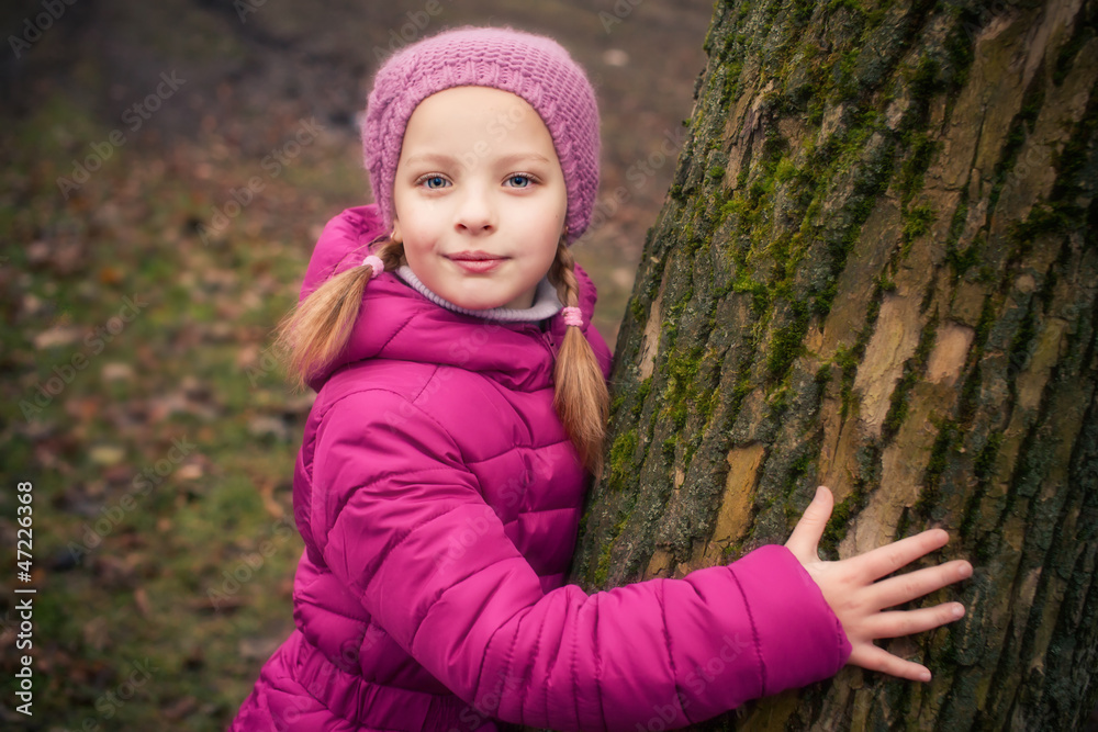 Little girl near tree in autumn or winter park. Little girl near tree in autumn or winter park.