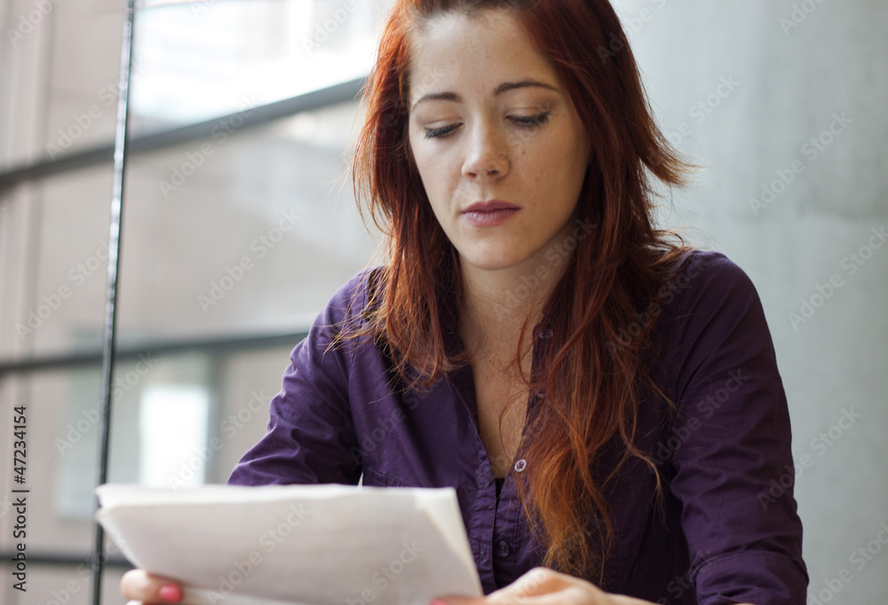 businesswoman reading over financial documents - speculating