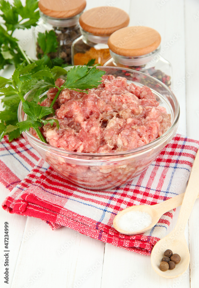 Bowl of raw ground meat with spices on wooden table Bowl of raw ground meat with spices on wooden table