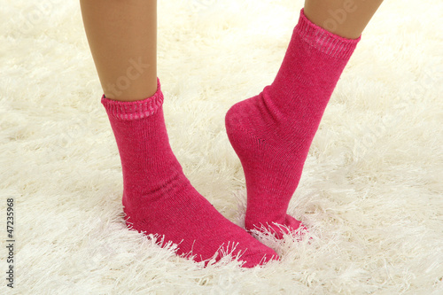 Female legs in colorful socks on  white carpet background