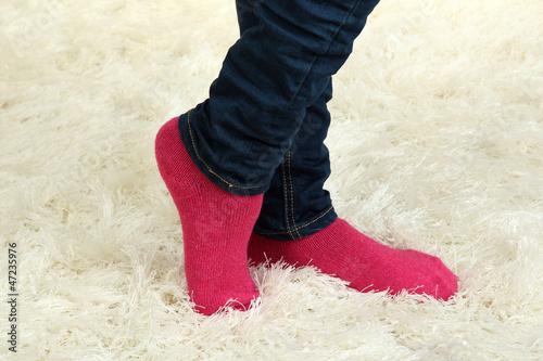 Female legs in colorful socks on  white carpet background