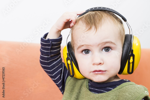 young child on couch with earmuffs