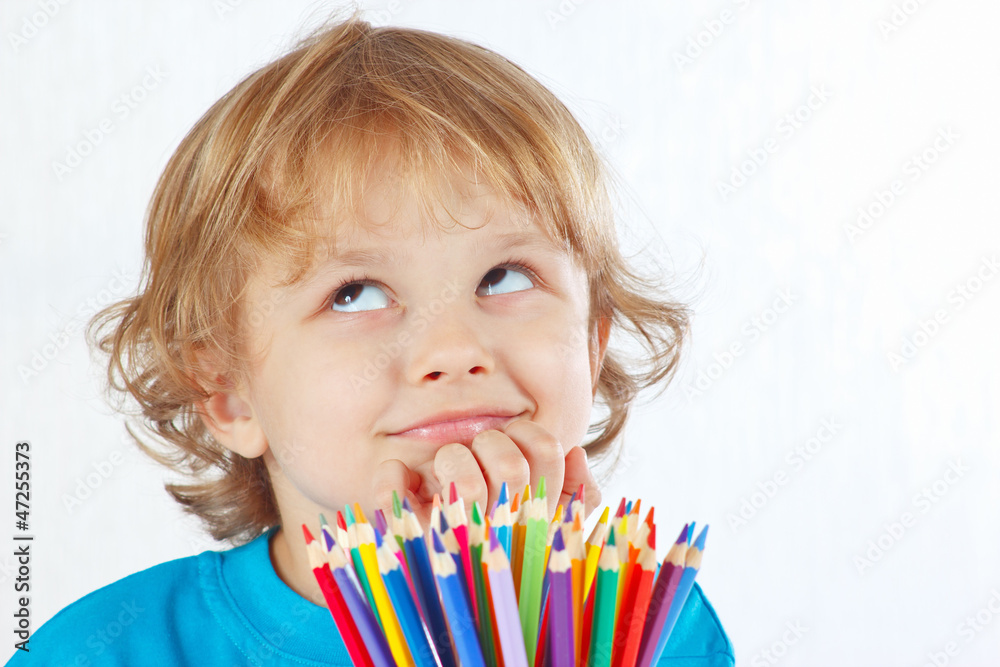 Young cute blond boy with color pencils on a white background Young cute blond boy with color pencils on a white background