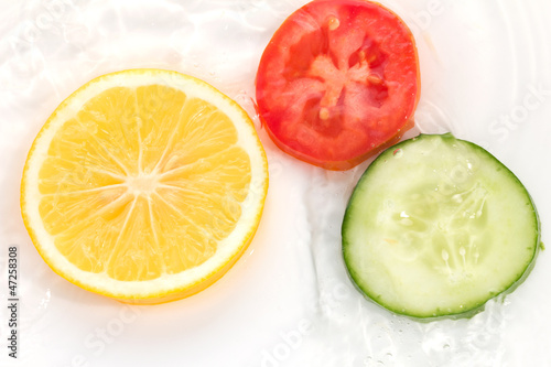 lemon cucumber and tomato in the water on a white background
