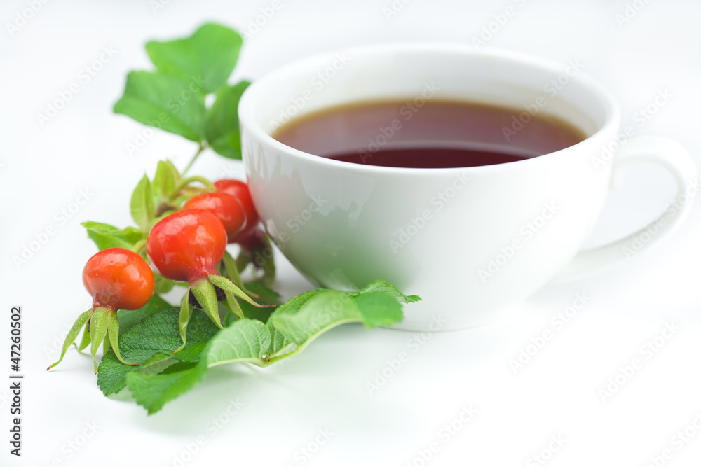 cup of tea and rosehip berries with leaves on white background cup of tea and rosehip berries with leaves on white background
