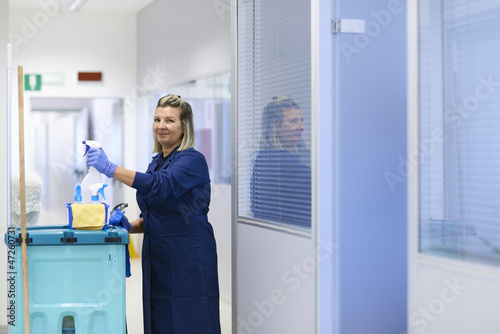 Portrait of happy professional female cleaner smiling in office photo