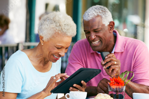 Senior Couple Using Tablet Computer At Outdoor Café