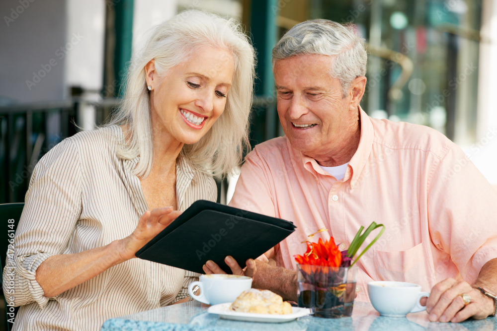 Senior Couple Using Tablet Computer At Outdoor Café Senior Couple Using Tablet Computer At Outdoor Café