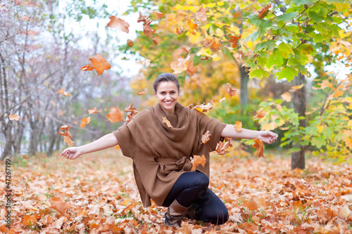 Obraz na plátně Woman throws autumn leaves