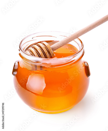 Glass jar of honey with wooden drizzler isolated on white