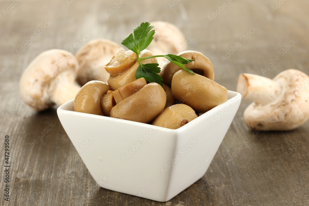 Delicious marinated mushrooms in bowl on wooden table close-up Delicious marinated mushrooms in bowl on wooden table close-up