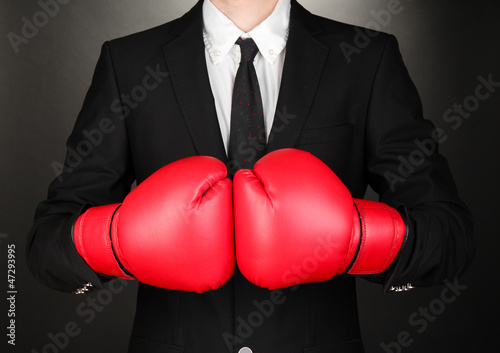 Businessman in boxing gloves on grey background © Africa Studio
